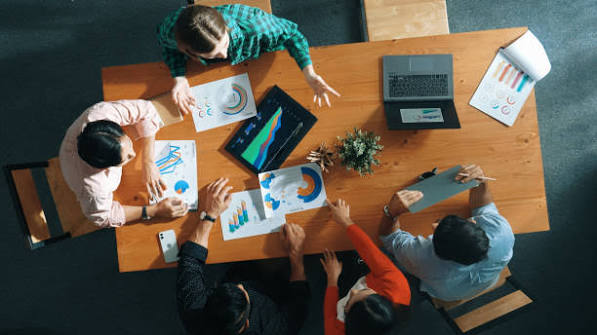 High-level strategic IT consulting meeting with a diverse team collaborating over data charts and technology from an aerial perspective in Canton, Ohio.